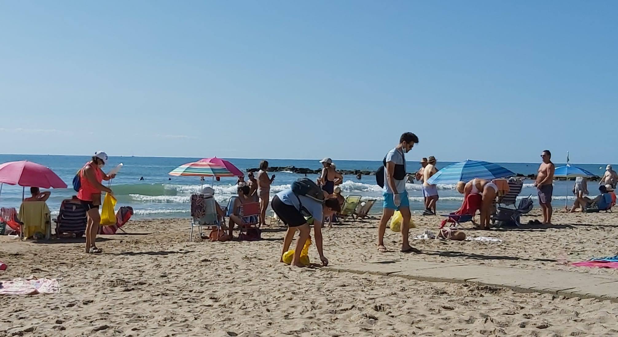 Voluntarios limpian la playa en Vilanova entre aplausos y pasividad de los bañistas